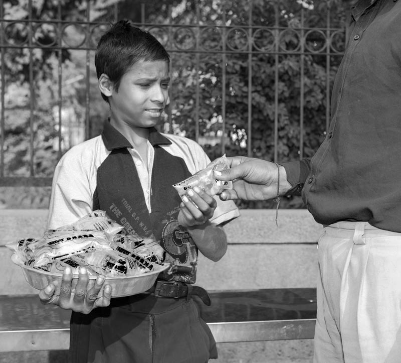 A boy doing brisk business by selling a packaged drinking water sachet on the roadside in Delhi